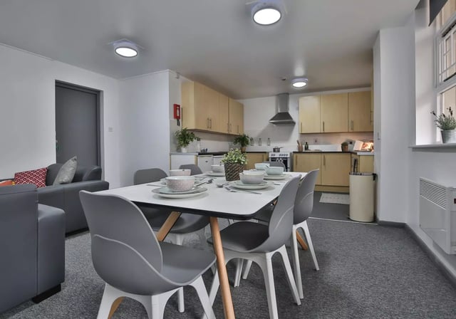 Dining table chairs kitchen cabinets and appliances living area at iQ Stephenson House in Newcastle Upon Tyne Student Accommodation