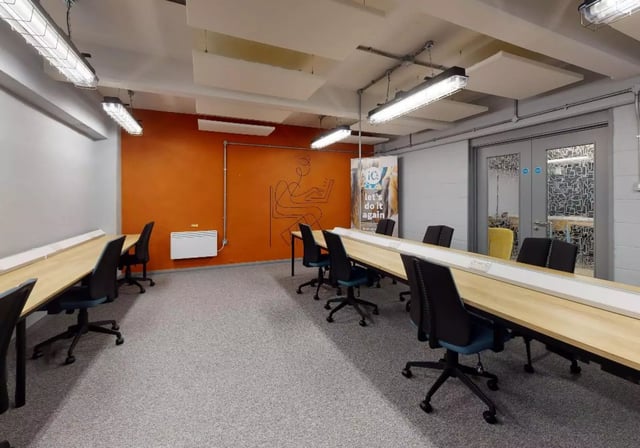 Desks with chairs and orange accent wall Study Area at iQ Stephenson House in Newcastle Upon Tyne Student Accommodation