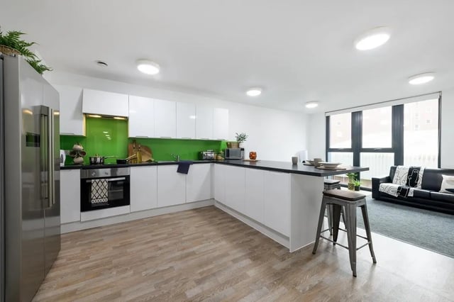 Modern white kitchen with island and seating area at Glassworks - Liverpool in Liverpool Student Accommodation