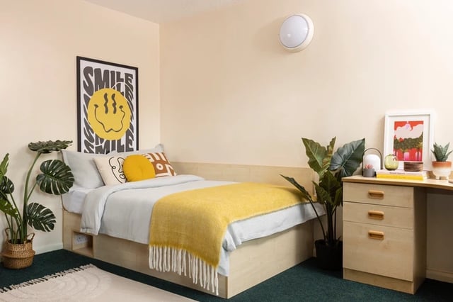 Bed with yellow throw and smile poster Bedroom at Leadmill Point in Sheffield Student Accommodation