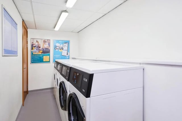 Laundry machines near door and posters laundry room at The Moor in Sheffield Student Accommodation