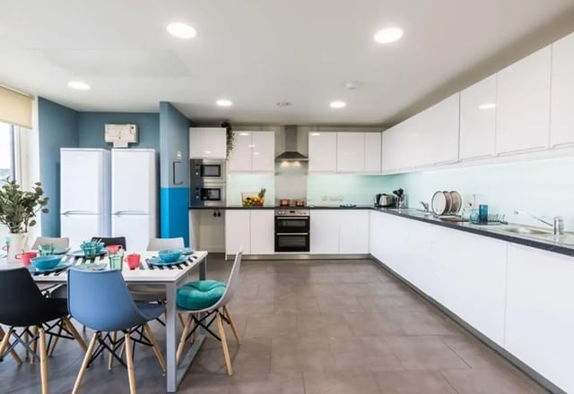 Table with chairs and modern kitchen with appliances Kitchen at Aparto Arbury Court in Kingston Upon Thames Student Accommodation
