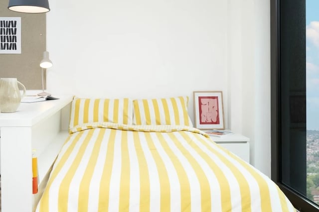 Bed with yellow striped duvet art and lamp bedroom at Scape Mile End in London Student Accommodation