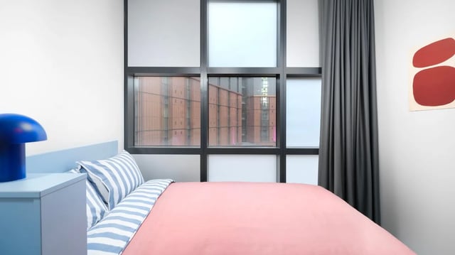 Blue lamp pink duvet striped pillows bedroom at Scape Mile End in London Student Accommodation