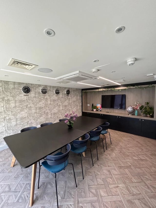 Long black table blue chairs wall clocks communal area at Opto Newcastle in Newcastle Upon Tyne Student Accommodation
