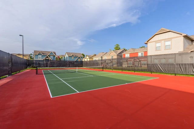 Tennis court with red and green surface and houses exterior at The Retreat West in Orlando Student Accommodation