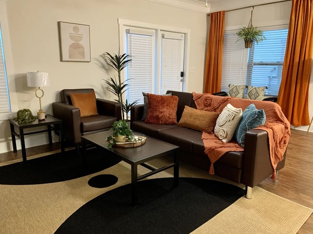 Brown leather sofa and chair with pillows living room at The Retreat West in Orlando Student Accommodation