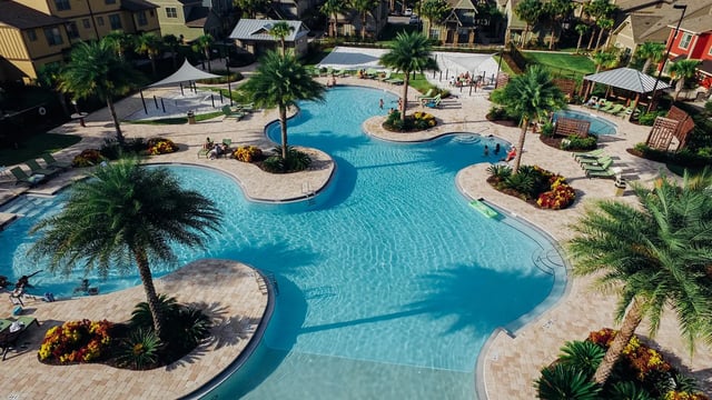 Large blue swimming pool with palm trees and lounge chairs pool area at The Retreat West in Orlando Student Accommodation