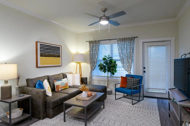 L-shaped sofa coffee table blue chair living room at The Retreat East in Orlando Student Accommodation