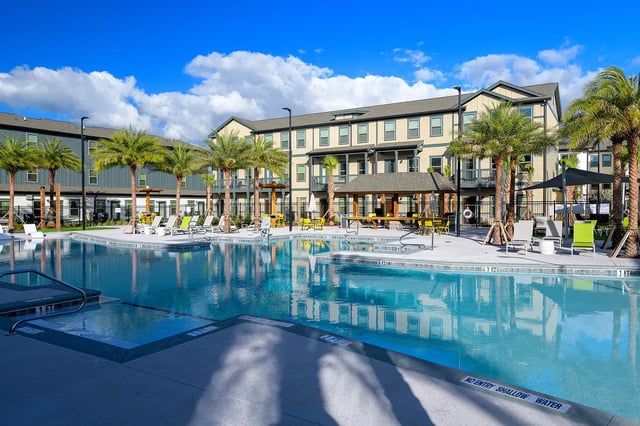 Swimming pool with lounge chairs and palm trees exterior at The Retreat East in Orlando Student Accommodation
