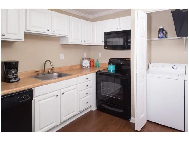 White cabinets sink coffee maker stove and washer kitchen at Seminole Flatts in Tallahassee Student Accommodation