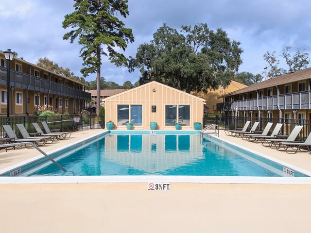 Pool with lounge chairs and buildings exterior at Seminole Flatts in Tallahassee Student Accommodation