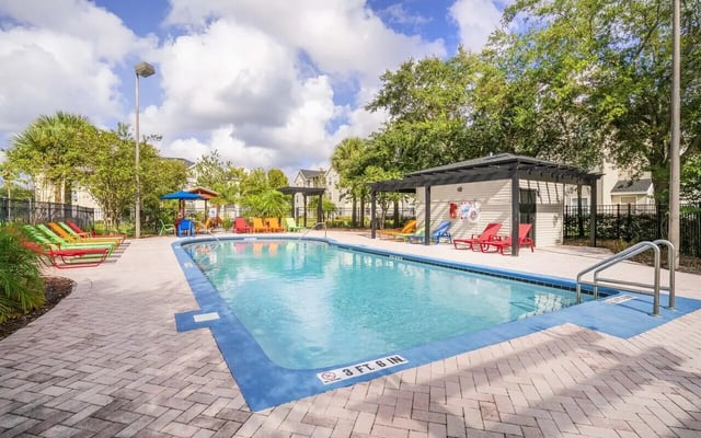 Pool with lounge chairs and covered seating area exterior at Pointe at Central in Orlando Student Accommodation