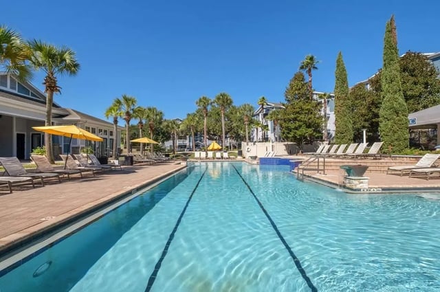 Swimming pool with lounge chairs and umbrellas playing area at West 10 in Tallahassee Student Accommodation