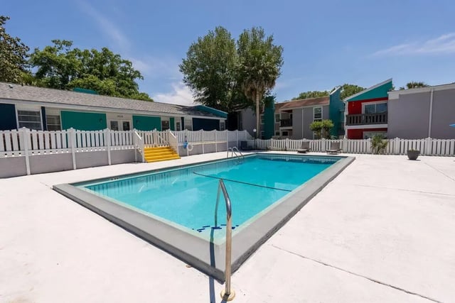 Blue swimming pool with lounge chairs and buildings Exterior at Vertex Tallahassee in Tallahassee Student Accommodation