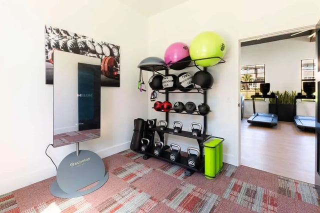 Exercise equipment with treadmills visible through doorway fitness room at The Annex at Campus West in Tallahassee Student Accommodation