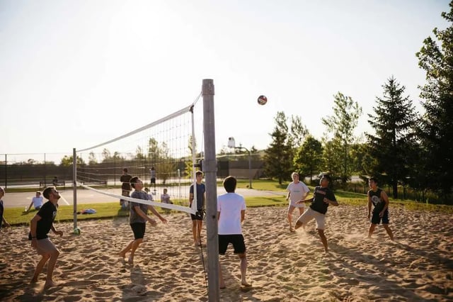 Students playing volleyball on sand court outdoor recreation area at The Annex at Campus West in Tallahassee Student Accommodation