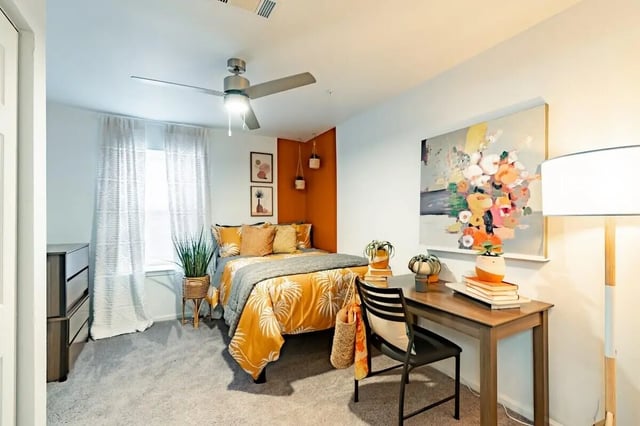 Bed desk plants artwork and lamp bedroom at The Annex at Campus West in Tallahassee Student Accommodation