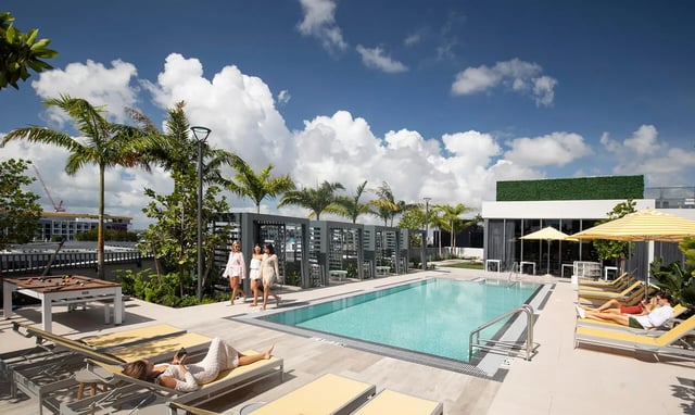 Pool lounge chairs umbrellas pool billiard table exterior at I5 WYNWOOD in Miami Student Accommodation