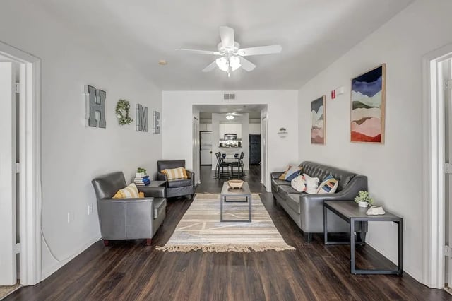 Sofa chairs rug coffee table kitchen visible living room at The Social Seminole in Tallahassee Student Accommodation