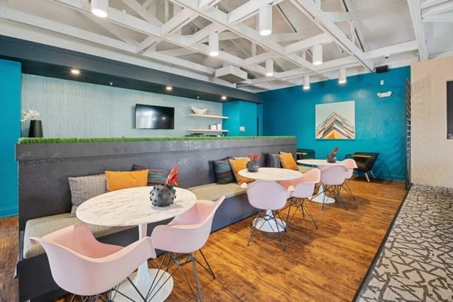 Sofa tables pink chairs and television common area at The Verge Orlando in Orlando Student Accommodation