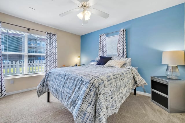 Bed with blue accent wall and ceiling fan bedroom at The Landing at Appleyard in Tallahassee Student Accommodation