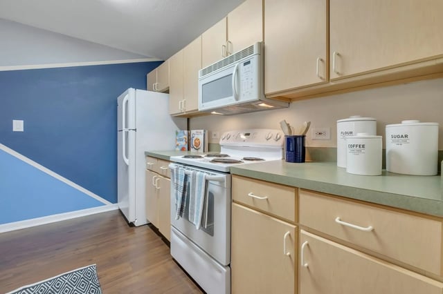 White appliances wood cabinets patterned rug kitchen at The Landing at Appleyard in Tallahassee Student Accommodation