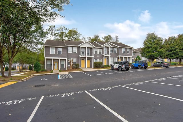 Apartment building with parking lot exterior at The Premier Townhomes at 1694 in Tallahassee Student Accommodation