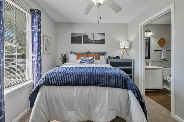 Bed with blue quilt bedside table and bathroom bedroom at Polo Club Tallahassee in Tallahassee Student Accommodation
