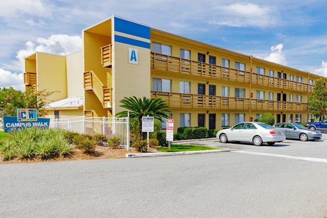 Yellow apartment building with balcony and parking exterior at Campus Walk Tallahassee in Tallahassee Student Accommodation
