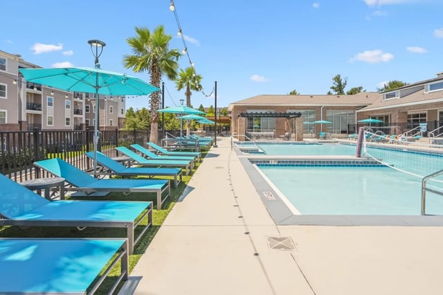 Poolside lounge chairs and umbrellas with swimming pool exterior at Oktiv in Tallahassee Student Accommodation