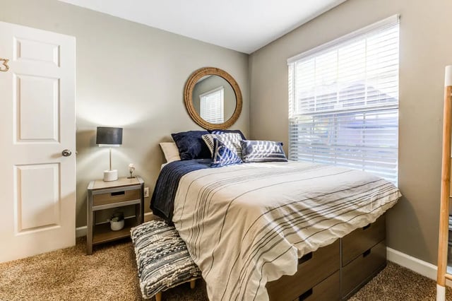 Bed with striped bedding bedside table mirror bedroom at Campus Row Tallahassee in Tallahassee Student Accommodation