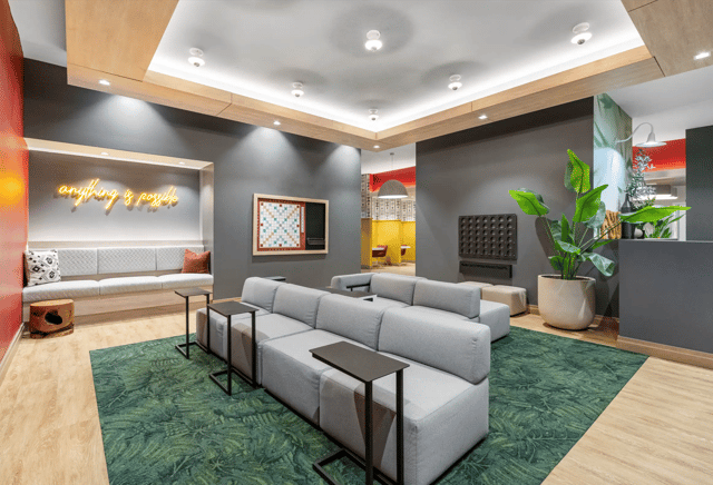 Gray sofas Scrabble board neon sign lounge area at Statehouse Tallahassee in Tallahassee Student Accommodation