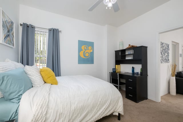 Bed with blue yellow pillows desk with chair Bedroom at The Crossing at Sante Fe in Gainesville Student Accommodation