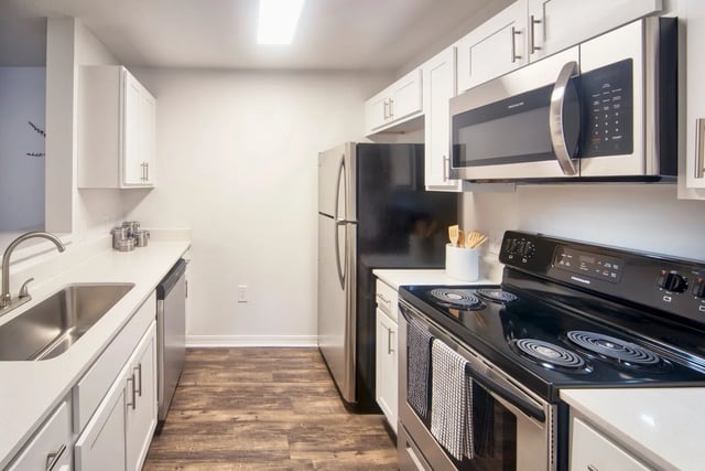 Stainless steel appliances white cabinets wood floor kitchen at The Crossing at Sante Fe in Gainesville Student Accommodation