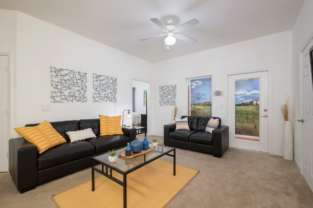 Black leather couches glass coffee table living room at The Crossing at Sante Fe in Gainesville Student Accommodation