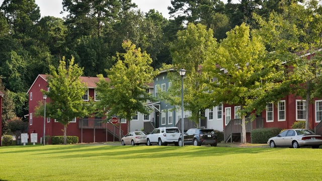Red and blue apartment buildings with cars exterior at The Preserve at San Luis in Tallahassee Student Accommodation