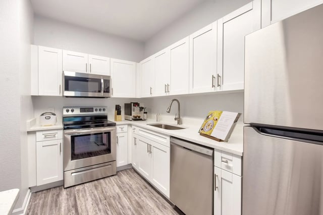 White cabinets stainless appliances sink and refrigerator kitchen at Gainesville Place in Gainesville Student Accommodation
