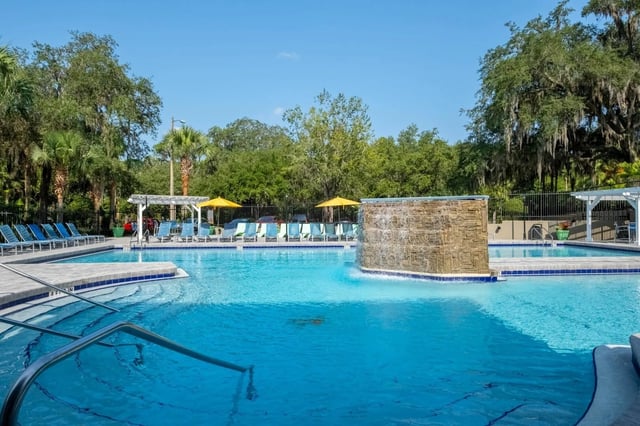Pool with lounge chairs and waterfall exterior at Gainesville Place in Gainesville Student Accommodation