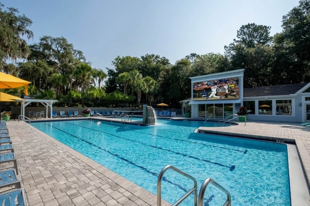 Pool with lounge chairs and outdoor screen playing baseball Exterior at Gainesville Place in Gainesville Student Accommodation