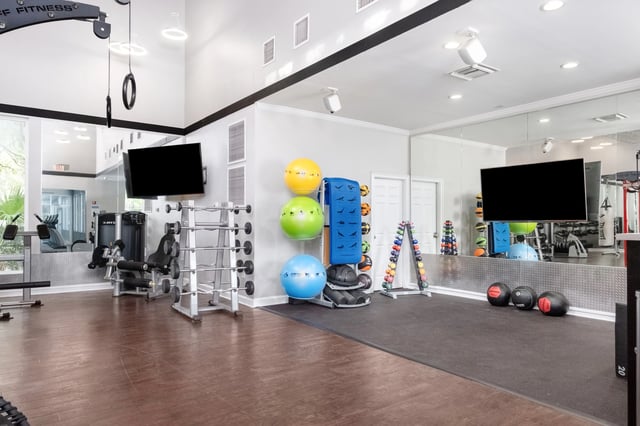 Weight racks exercise balls TVs and equipment fitness room at Gainesville Place in Gainesville Student Accommodation