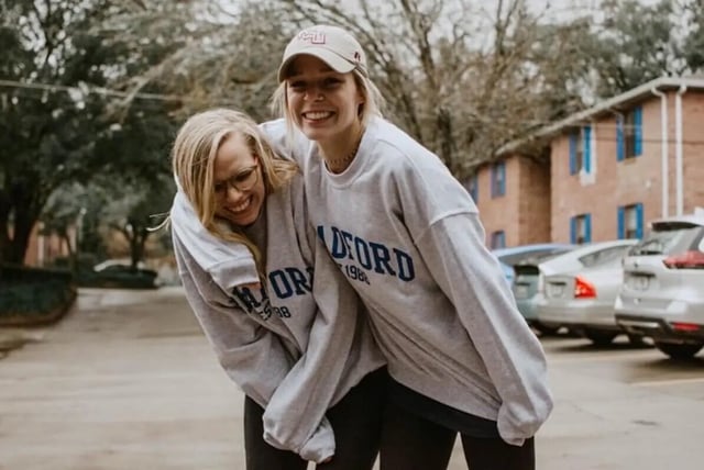 Two students smiling with buildings exterior at Bradford Oaks in Tallahassee Student Accommodation