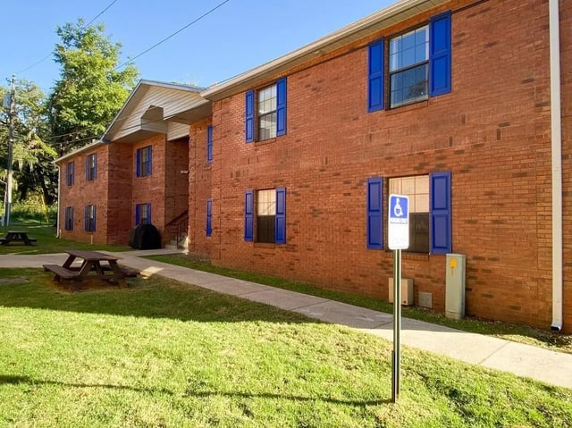 Brick building blue shutters and picnic tables exterior at Bradford Oaks in Tallahassee Student Accommodation