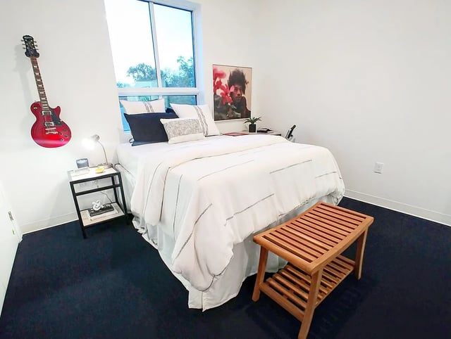 Red guitar bed nightstand wooden bench bedroom at Midtown Gainesville in Gainesville Student Accommodation