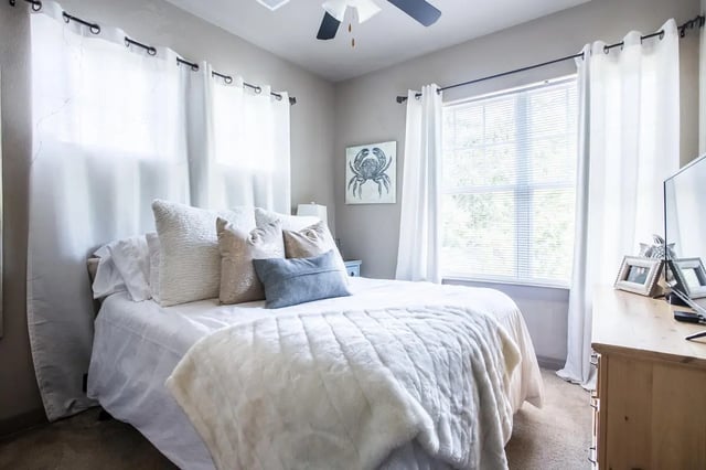 Bed with white linens plush throw crab art bedroom at CollegePlace - Elements in Tallahassee Student Accommodation