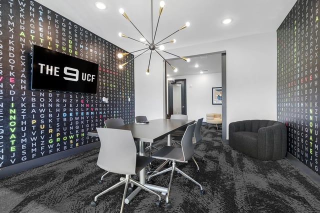 Study area with conference table dark sofa and chairs living room at The 9 UCF in Orlando Student Accommodation