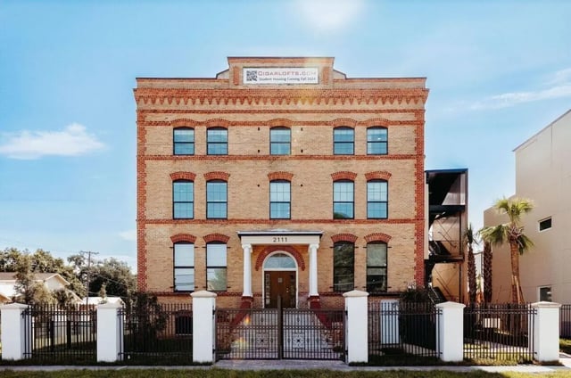 Brick building with fence and stairs exterior at CigarLofts in Tampa Student Accommodation