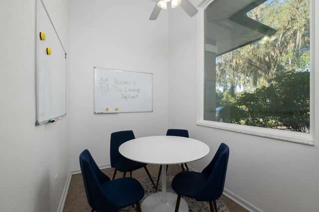 White table four blue chairs whiteboards study room at The Landings Gainesville in Gainesville Student Accommodation