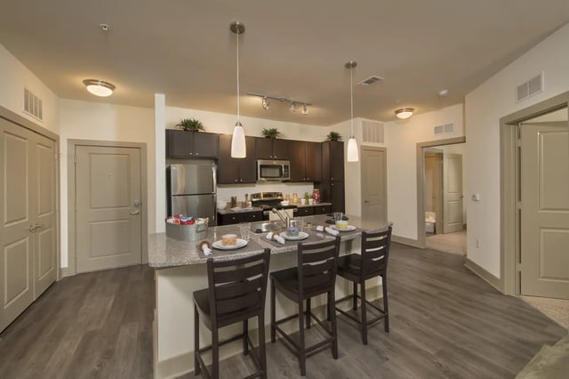Kitchen island with chairs refrigerator stove and cabinets kitchen at Saga Tallahassee in Tallahassee Student Accommodation