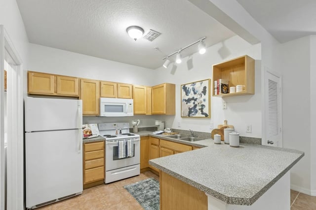 Kitchen with white appliances wood cabinets and counter space kitchen at Lux 13 in Gainesville Student Accommodation